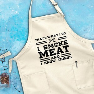 May include: White cotton apron with a black print that says "That's what I do I smoke meat and I know things".