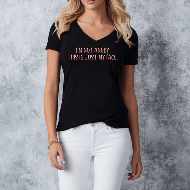May include: A black v-neck t-shirt with the text "I'm not angry. This is just my face." in a pink and white gradient.
