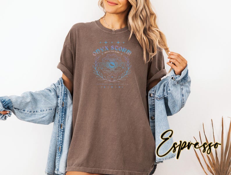 May include: A brown t-shirt with a graphic print of a stylized eye with the text "Only Scorpio What You See Here" in a rainbow gradient.