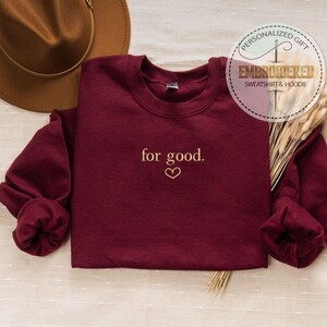 May include: Burgundy sweatshirt with the text "for good." embroidered in gold on the front.