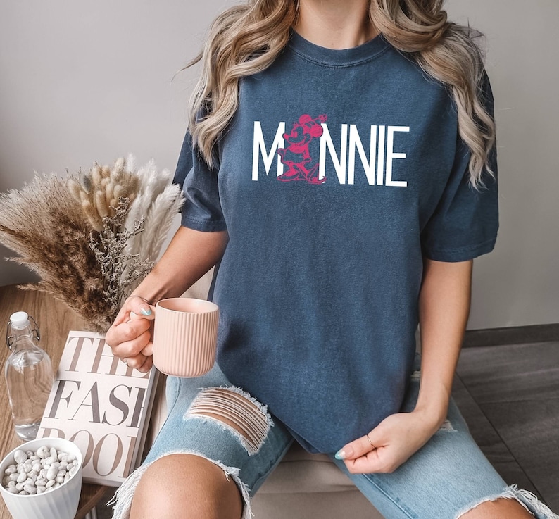 May include: A navy blue t-shirt with a white graphic of Minnie Mouse and the text "MINNIE" in white.