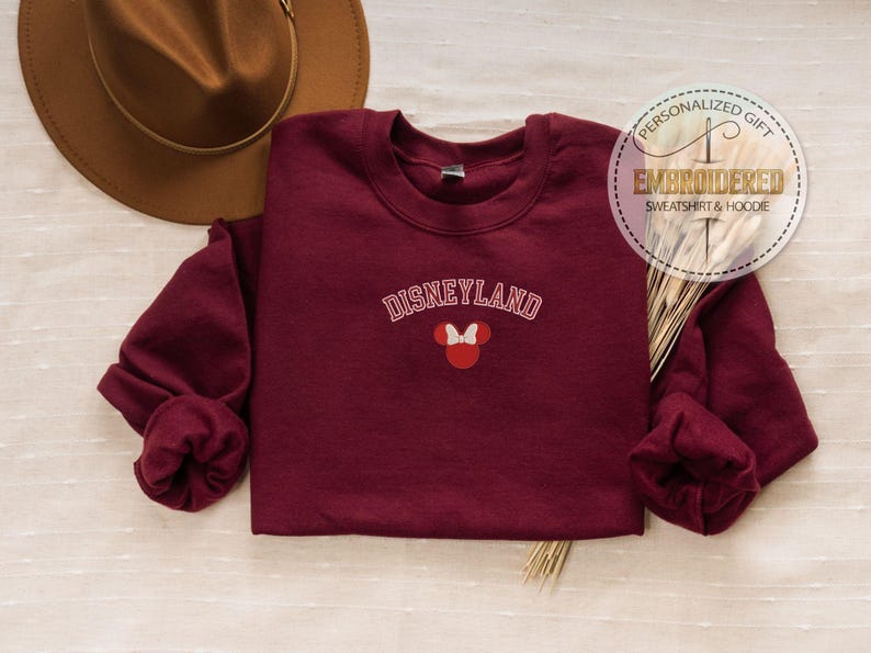 May include: Burgundy sweatshirt with the text "DISNEYLAND" in white with a red and white Mickey Mouse silhouette.