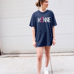 May include: A navy blue t-shirt with a white graphic of Minnie Mouse and the word "MINNIE" in white letters.