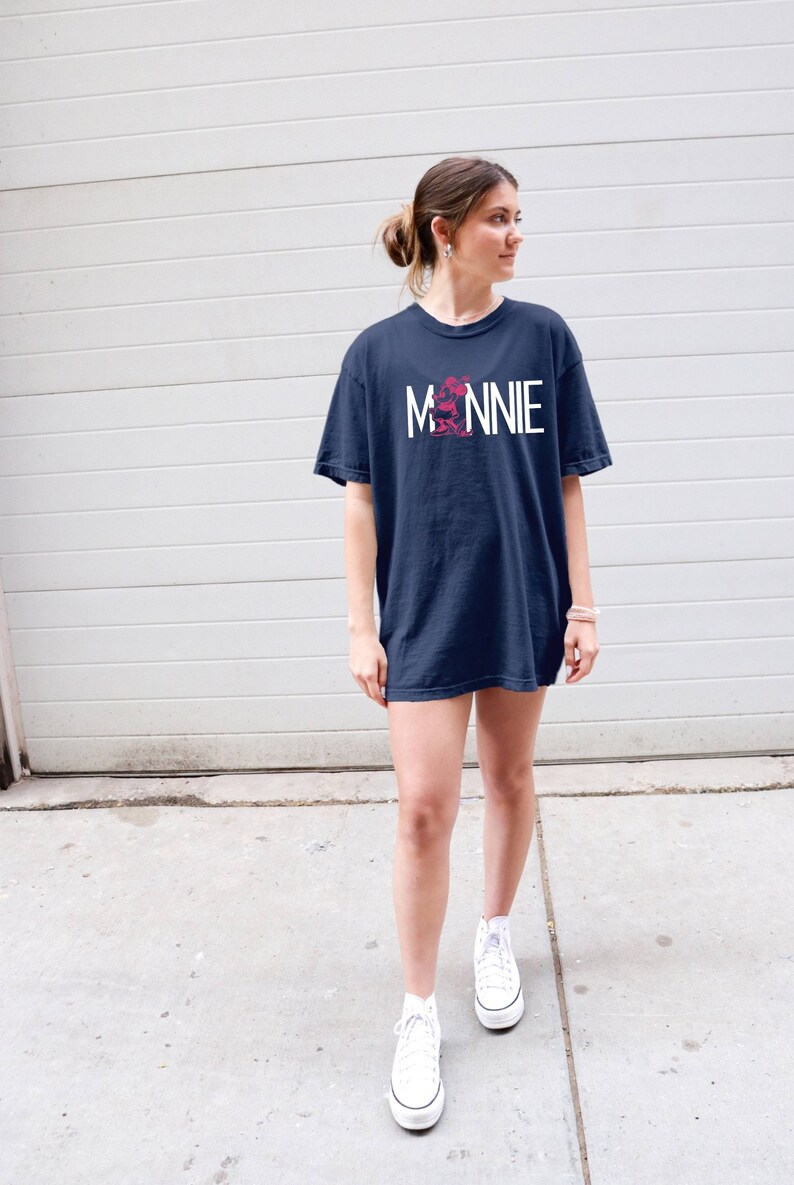 May include: A navy blue t-shirt with a white graphic of Minnie Mouse and the word "MINNIE" in white letters.