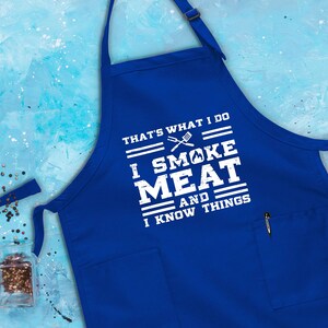 May include: Blue apron with a white graphic that says "That's what I do I smoke meat and I know things".