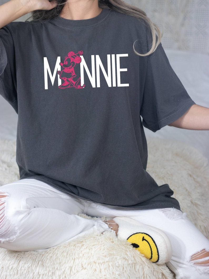 May include: A gray oversized t-shirt with a white graphic of Minnie Mouse and the word "MINNIE" printed on the front.