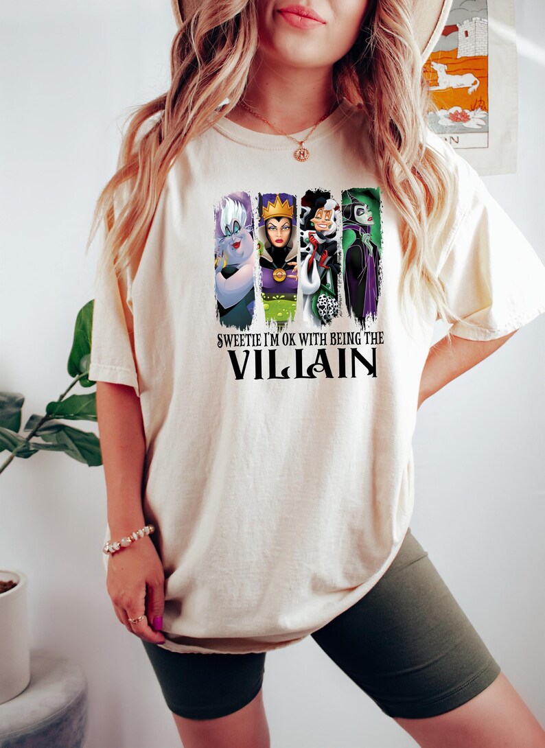 Pu&ograve; includere: T-shirt color crema con un disegno di quattro cattivi dei cartoni animati, tra cui Ursula, la Regina Cattiva, Crudelia De Mon e Malefica. Il testo sulla maglietta dice "Sweetie I'm OK with being the Villain".