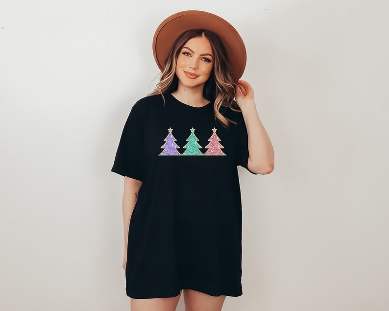 May include: A black t-shirt with a design of three glitter Christmas trees in pink, green, and purple.