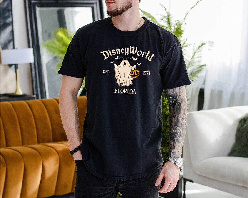 May include: Black t-shirt featuring a white ghost holding a pumpkin and the text "DisneyWorld est 1971 FLORIDA".