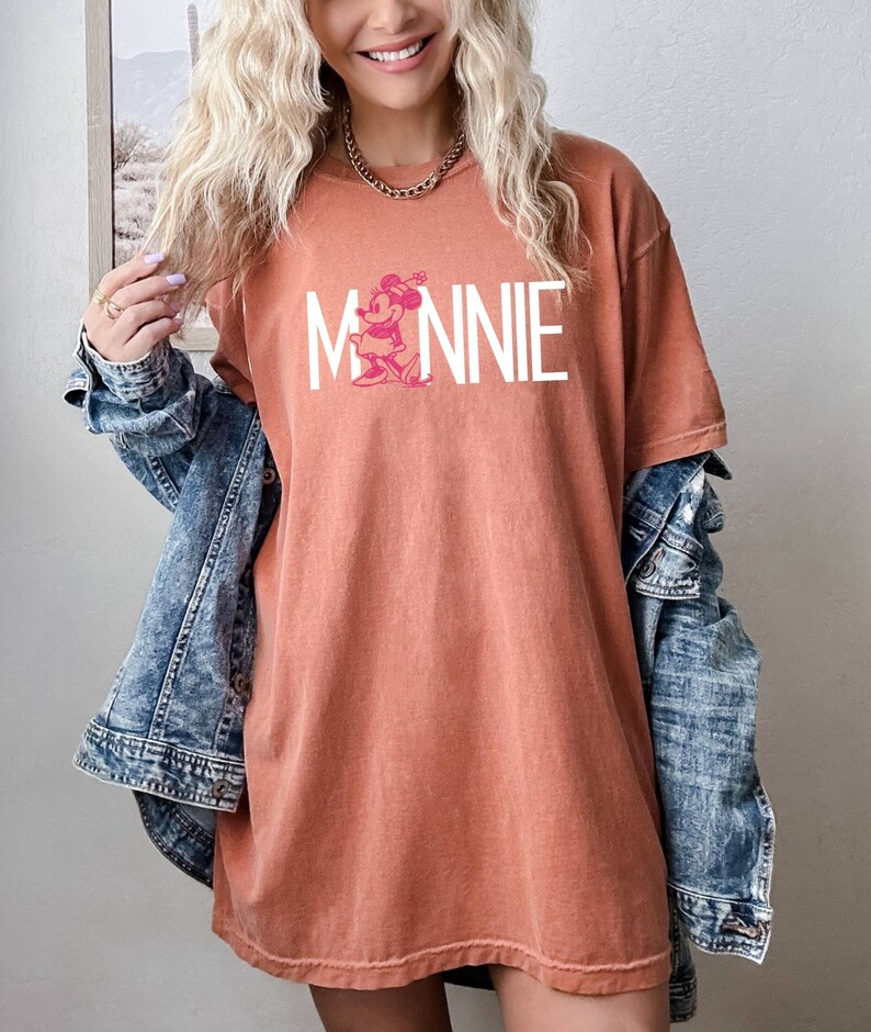 May include: A rust-colored oversized t-shirt with a white graphic of Minnie Mouse and the word "MINNIE" in white letters.