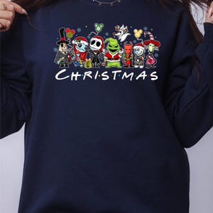 Pu&ograve; includere: Felpa blu navy con una stampa grafica di vari personaggi dei cartoni animati, tra cui Jack Skellington, il Grinch e Oogie Boogie. Il testo "CHRISTMAS" &egrave; stampato sotto i personaggi.