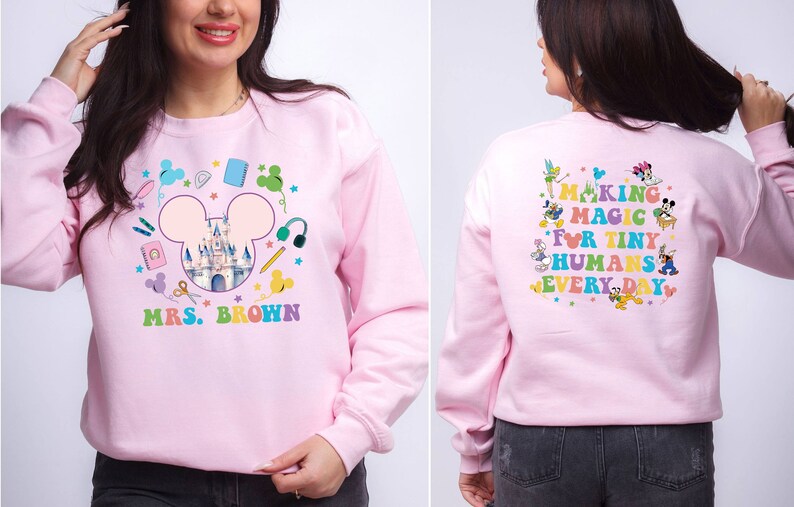Puede incluir: Sudadera rosa claro con un dise&ntilde;o colorido de Disney. La parte delantera presenta un castillo dentro de un contorno de la cabeza de Mickey, &uacute;tiles escolares y "MRS. BROWN". La parte trasera dice "MAKING MAGIC FOR TINY HUMANS EVERY DAY" con personajes de Disney.