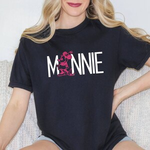 May include: Black t-shirt with a white graphic of Minnie Mouse and the word "MINNIE" in white letters.