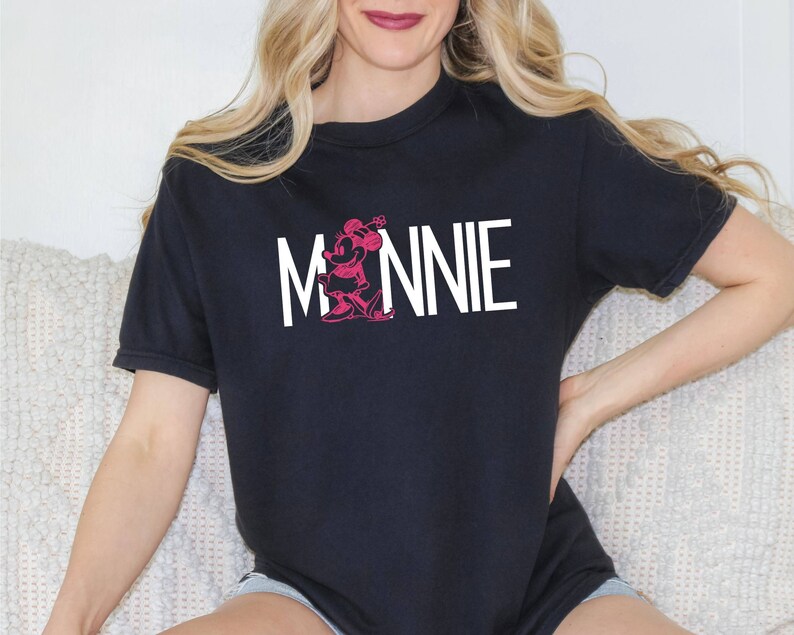 May include: Black t-shirt with a white graphic of Minnie Mouse and the word "MINNIE" in white letters.