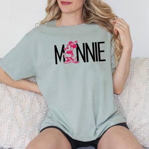May include: A light green t-shirt with a pink Minnie Mouse graphic and the text "MINNIE" in black.