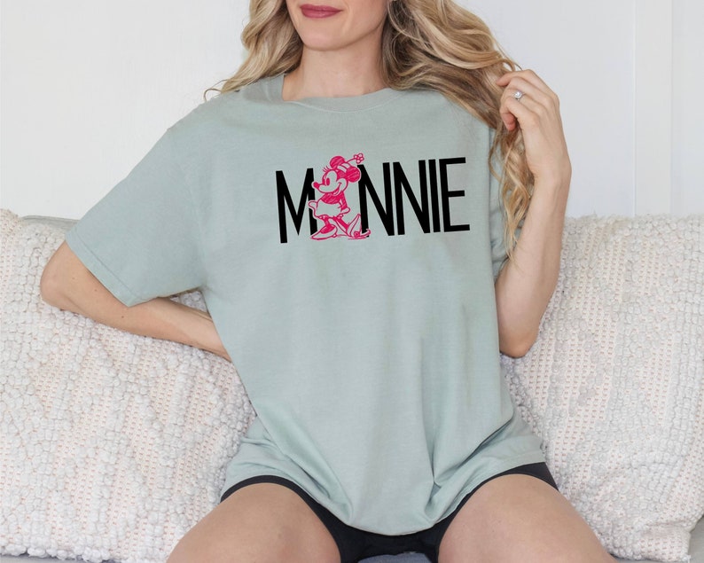 May include: A light green t-shirt with a pink Minnie Mouse graphic and the text "MINNIE" in black.