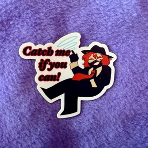 May include: A sticker featuring a cartoon character in a black suit, red tie, and hat, with red hair and a mask. The text "Catch me if you can!" is written above the character.