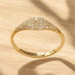 May include: A gold ring with a curved top set with small diamonds. The ring is marked "NORM 14K" on the inside.