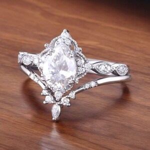 Puede incluir: Un anillo de compromiso de diamante de forma pera con un engaste delicado y ornamentado. El anillo presenta una banda con un dise&ntilde;o delicado e intrincado y un diamante de forma pera en el centro.