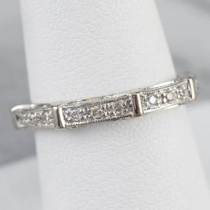 K&ouml;nnte beinhalten: Ein zartes Silberband mit einer Reihe kleiner, funkelnder Diamanten, die in einem dekorativen Muster eingefasst sind.