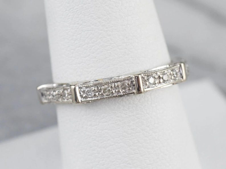 K&ouml;nnte beinhalten: Ein zartes Silberband mit einer Reihe kleiner, funkelnder Diamanten, die in einem dekorativen Muster eingefasst sind.