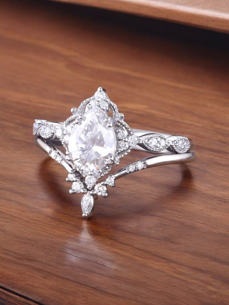 Puede incluir: Un anillo de compromiso de diamante de forma pera con un engaste delicado y ornamentado. El anillo presenta una banda con un dise&ntilde;o delicado e intrincado y un diamante de forma pera en el centro.
