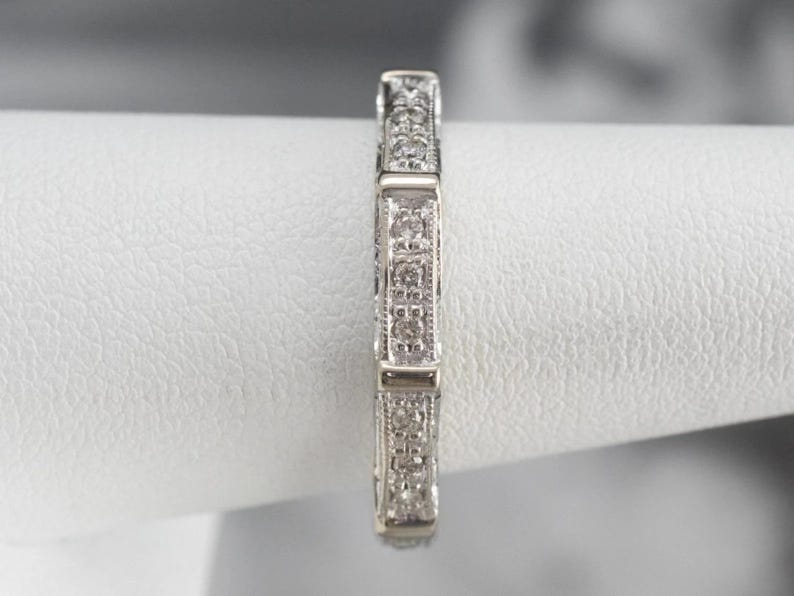 K&ouml;nnte beinhalten: Ein silberner Bandring mit einem filigranen, komplizierten Design, das mit kleinen Diamanten in Pav&eacute;-Fassung besetzt ist.