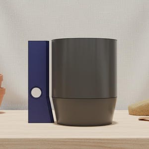 May include: A still life composition featuring a dark gray cylindrical object, a blue binder, and several terracotta pots. A sponge, a small bowl, and a wooden tool are also present. The objects are arranged on a light wooden surface.