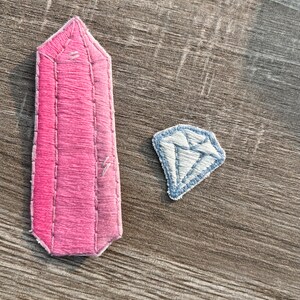 May include: Two embroidered patches, one pink and one blue, shaped like a crystal and a diamond.