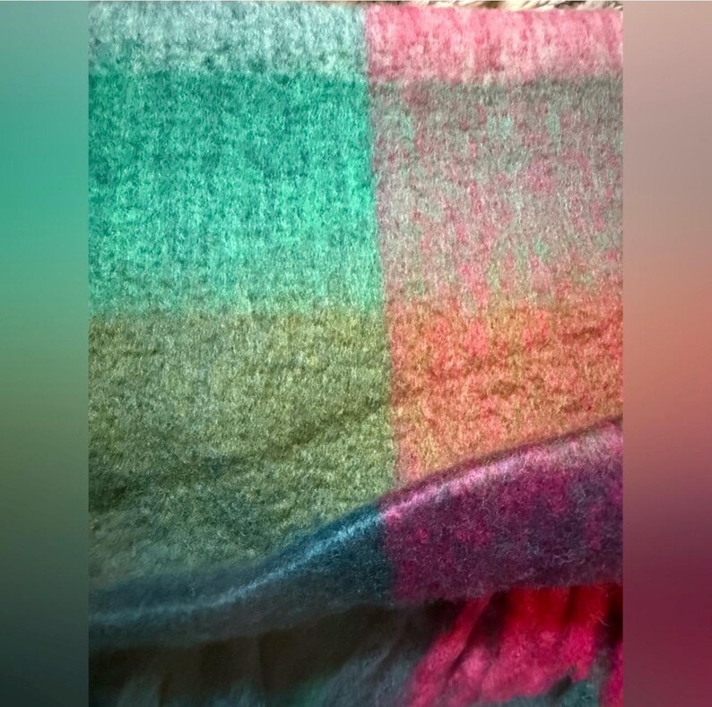 May include: A large, patterned scarf in a plaid design. The scarf displays blocks of teal, green, pink, and purple. The fabric has a soft, textured appearance, ideal for colder weather. A warm and stylish accessory.