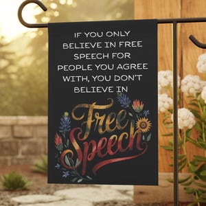 May include: A black garden flag with the words "IF YOU ONLY BELIEVE IN FREE SPEECH FOR PEOPLE YOU AGREE WITH, YOU DON'T BELIEVE IN Free Speech" in white and colorful script. The flag is displayed on a black metal stand.