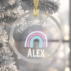 May include: A clear glass Christmas ornament with a rainbow design and the text "First Christmas as Alex".
