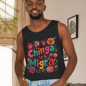 May include: Black tank top with a colorful floral design and the text "Chinga la Migra" in bright colors. The design includes flowers, maracas, and other decorative elements. The tank top is sleeveless.