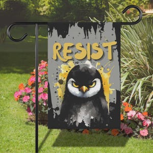 May include: A black and gray garden flag with a cartoon penguin with angry eyes and the word "RESIST" in yellow letters.