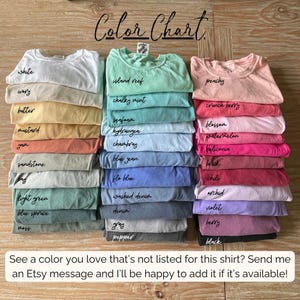 May include: A color chart displays stacks of t-shirts in various colors, including white, island reef, and peachy. The text "Color Chart" is at the top. The bottom text reads, "See a color you love that's not listed for this shirt? Send me an Etsy message..."