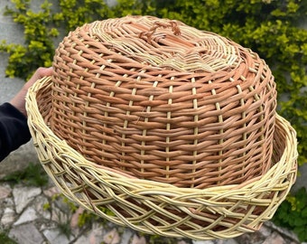 Op de afbeelding: Een geweven rieten manddeksel in lichtbruine en beige tinten. Het deksel heeft een geweven handvat en een decoratieve rand.