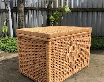 May include: A rectangular wicker storage chest with a hinged lid. The chest is woven from light brown wicker and features a diamond pattern on the front. The chest is designed for storage and has a natural, rustic appearance.