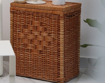 May include: A wicker storage basket with a lid, featuring a woven pattern. Three candles and a white ceramic sculpture with a floral design are on top of the basket.