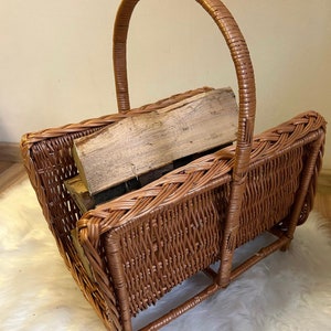 May include: A brown wicker log basket with a woven handle. The basket is filled with pieces of firewood.