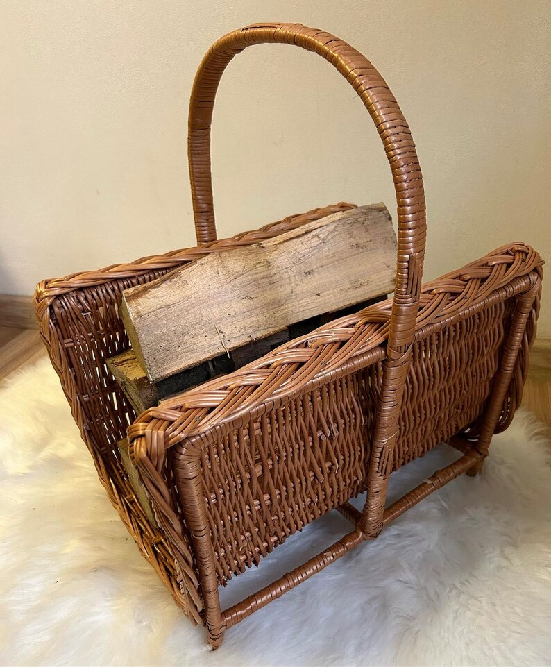 May include: A brown wicker log basket with a woven handle. The basket is filled with pieces of firewood.