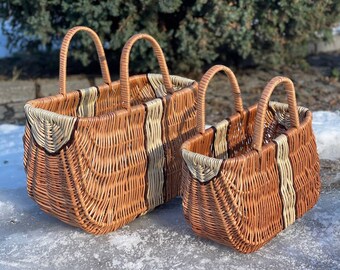 May include: Two woven wicker baskets with handles. The larger basket is brown with white stripes and the smaller basket is brown with cream stripes.