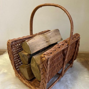 May include: A brown wicker log basket with a handle. The basket is filled with logs of wood.