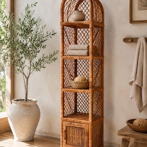 May include: A tall, arched brown wicker shelving unit featuring four open shelves and a single cabinet door at the base. The sides and back are constructed with a diamond-patterned lattice weave, while the cabinet door features vertical slats.