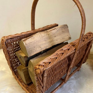 May include: A woven wicker log basket with a handle. The basket is filled with stacked pieces of firewood.