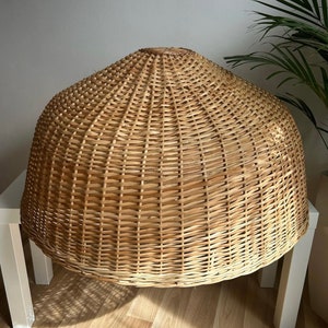 May include: A large, round, natural woven wicker lampshade. The shade is made of light brown, natural wicker and has a dome shape.