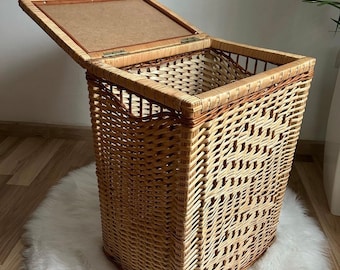 May include: A woven wicker storage basket with a hinged lid. The basket is made of natural brown and light brown wicker and has a rectangular shape.