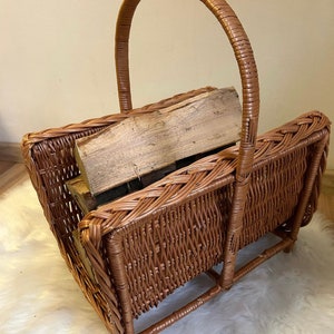 May include: A brown wicker log basket with a handle. The basket is filled with wooden logs.