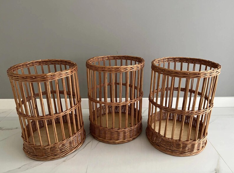 Puede incluir: Tres cestas cil&iacute;ndricas fabricadas en mimbre marr&oacute;n natural. Cada cesta presenta un dise&ntilde;o de listones verticales con una base tejida reforzada y un fondo plano de madera clara. Los recipientes abiertos tienen una estructura uniforme.