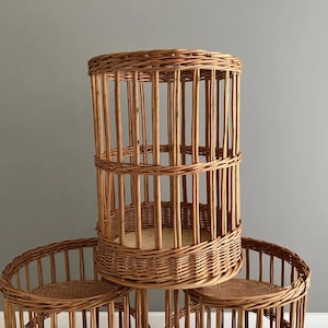 Puede incluir: Un conjunto de tres soportes cil&iacute;ndricos de mimbre con un acabado natural en color marr&oacute;n claro. Cada soporte est&aacute; construido con juncos trenzados verticales que forman una estructura de jaula, una base circular s&oacute;lida y un borde reforzado.