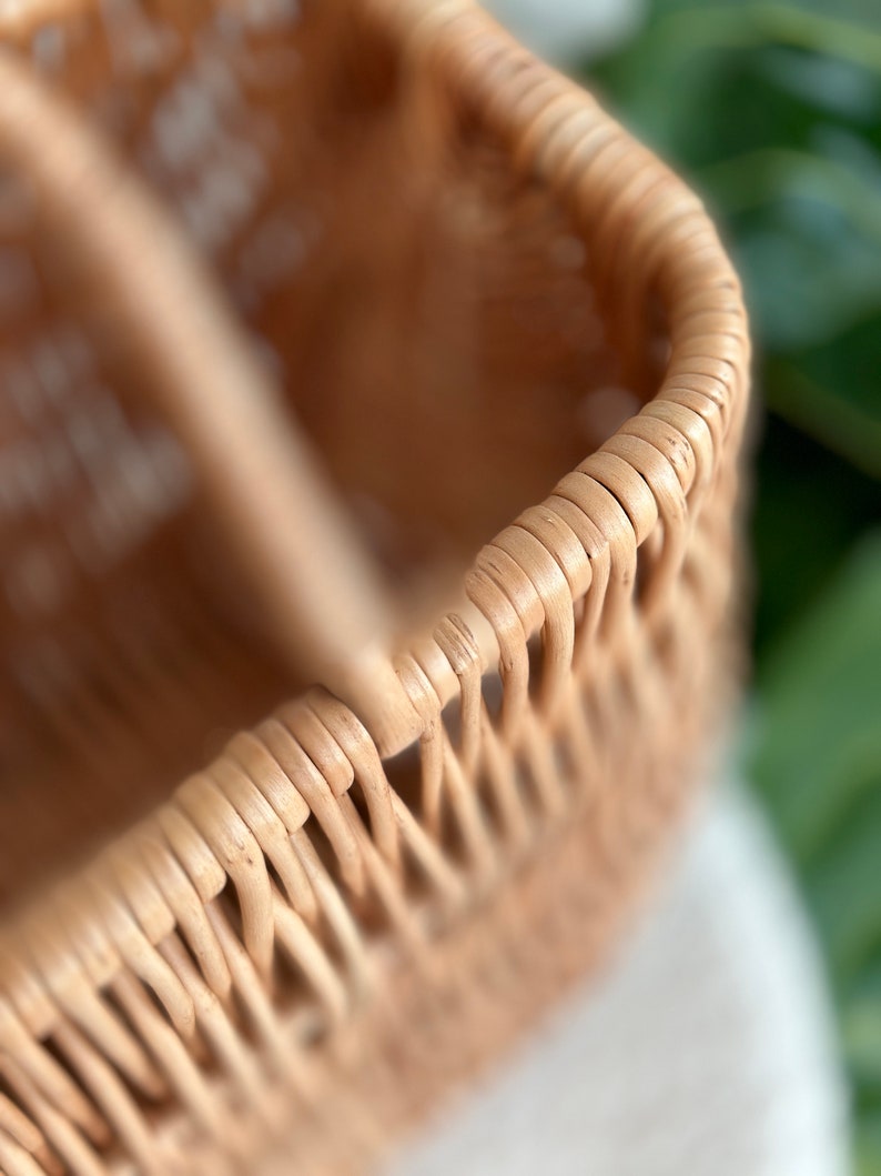 May include: Close-up of a woven wicker basket with a natural brown color. The basket is made of thin, tightly woven strips of rattan.